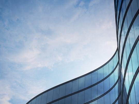 Perspective of high rise building and dark steel window system with clouds reflected on the glass