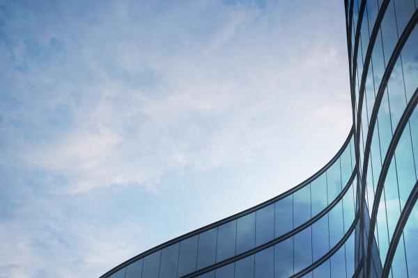 Perspective of high rise building and dark steel window system with clouds reflected on the glass